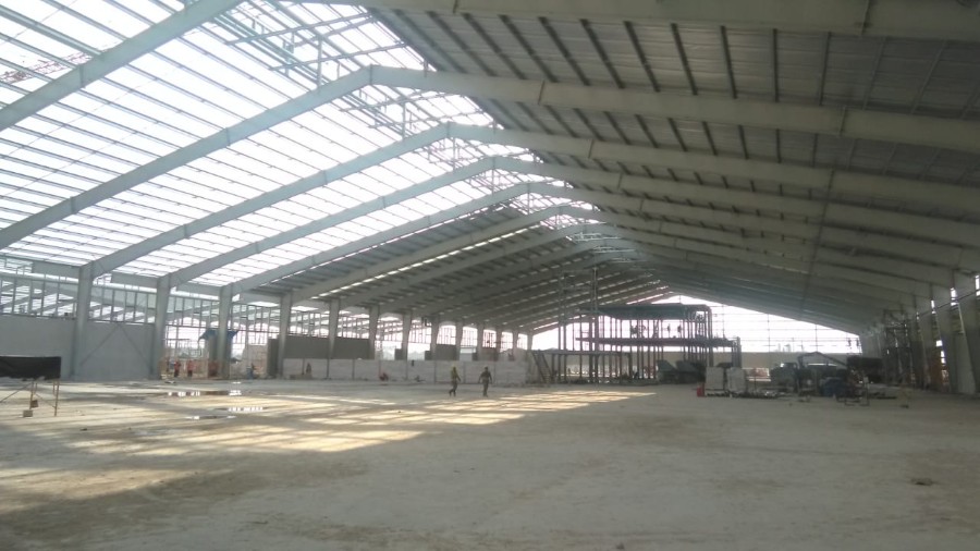 Roof cladding installation on the prefabricated steel building, enhancing its weatherproof envelope