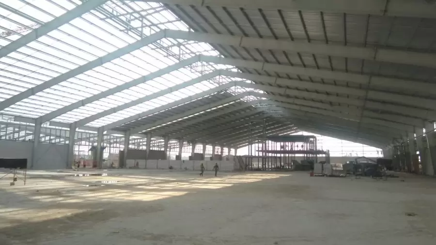 Roof cladding installation on the prefabricated steel building, enhancing its weatherproof envelope